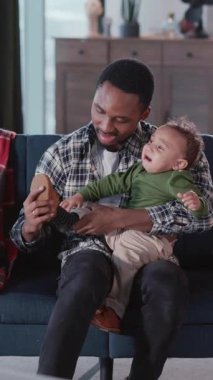 Huzurlu genç baba, oturma odasında ağlayan küçük, güzel çocuğu sakinleştiriyor. Çocuklar, duygular ve yetiştirilme konsepti.