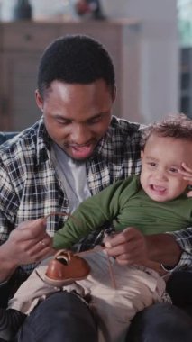 Genç Afro-Amerikan erkek baba dışarı çıkmak için giyinirken ağlayan güzel bir oğlan çocuğu sakinleştiriyor. Babalık kavramı, yetiştirilme anlayışı.