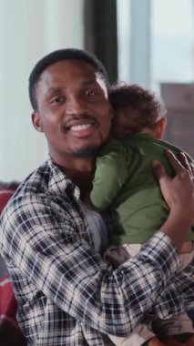 Genç Afrikalı yakışıklı adam portresi, elinde ağlayan bir bebekle evde birlikte vakit geçiriyor. Portreler. Aileler. Yetiştirme.