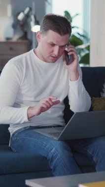 Genç Kafkasyalı ofis çalışanı, laptopla iletişim kuruyor. Akıllı telefonlara cevap veriyor. Evde kalıyor..