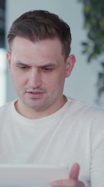 Genç, yakışıklı, beyaz iş adamı. Evde kalıp iş arkadaşlarıyla tabletle şirket toplantılarında görüntülü sohbet ediyor..