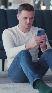 Sıradan yakışıklı bir genç adam cep telefonu uygulaması kullanıyor. İnternette sörf yapıyor, haberleri okuyor. Dairedeki kanepeye yaslanıyor..