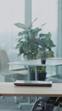 Kurumsal genç adam siyah tekerlekli sandalyede sakat. Bilgisayarla masaya taşınıyor. Ağ bağlantısı kuruyor..