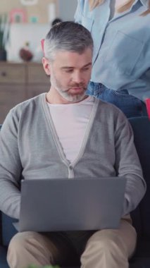 Laptop üzerinde çalışan beyaz, çekici, yetişkin bir adam karısıyla kahve içiyor. Neşeli koca portresi. Serbest çalışan, kameraya gülümseyen kahve içen..