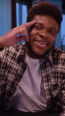 Çağdaş bir ortamda, genç bir adam düşünceli bir pozda oturur, derin bir anlık yansıma ve içgözlem altında.