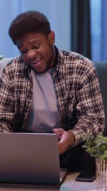 Genç bir adam evinde rahat bir ortamda dinlenirken bilgisayarında büyüleyici bir online deneyimden zevk alıyor.