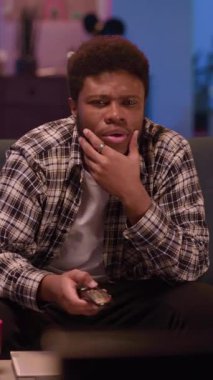 Genç bir adam, rahat ve davetkar bir oturma odası ortamında heyecan verici bir video oyunu oynamakla meşgul.