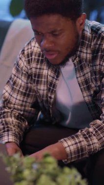 Genç bir adam şık bir iç mekan ortamında yoğun bir konsantrasyon gösteren gösterişli bir cihaza dikkatle odaklanır.