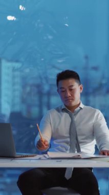 Kendini işine adamış bir işadamı çarpıcı şehir manzaralı modern bir ofiste önemli belgeleri inceliyor.