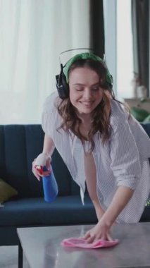 Kulaklık takmış, müzik dinleyen, tozdan evi temizleyen seksi, genç bir kadın. Evi düzenliyorum. Ev temizliği.