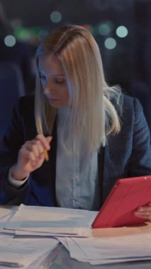 Tablet uygulama bilgisayarı kullanan akıllı yönetici genç iş kadını rapor yazma finans projesi sunumu gece ofis içlerinde son teslim tarihine kadar çalışıyor.