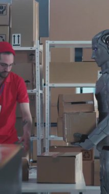 İnsan ve Robot İşbirliği. Sibernetik Cyborg 'un Ağır Kutuları Taşıması, Kafkasyalı Genç Erkek Yöneticisi' nin Postanedeki Paketlerine Yardım Ediyor.