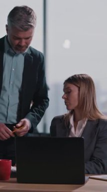 Bir erkek ve bir kadın, masa başında dizüstü bilgisayarla, takım çalışması sergileyerek odaklanmış bir tartışmaya giriyorlar. Kadına yakın çekim, bağımsız düşüncelerini vurguluyor.