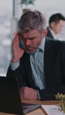 Modern bir ofiste, keskin takım elbiseli bir adam özenle dizüstü bilgisayarı üzerinde çalışır, sakin ve üretken bir ortamda profesyonellik ve kendini adamışlık gösterir.