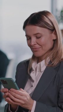 Bu ilgi çekici videoda, akıllı takım elbiseli profesyonel bir kadın telefonuyla etkileşime geçiyor, konsantrasyondan eğlenceye duygularını gösteriyor. Bu teknoloji ve modern iş hayatının karışımını vurgular.