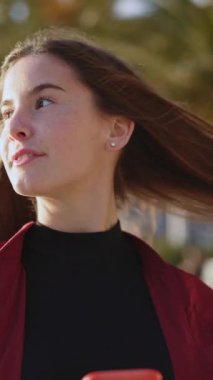 Akıllı telefon kullanan, selfie çeken, kumsalda yürürken saçını okşayan beyaz bir kız öğrenci. Yaz zamanı. Gençlik kavramı.