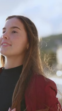 Sahil boyunca cep telefonuyla yürüyen neşeli, samimi, genç bir kadın. Güzel kız portresi. Turizm konsepti. Yaz seyahati.