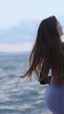 Çekici seksi genç sporcu. Kumsalda koşup kulaklıkla akıllı telefon dinlerken eğleniyor..