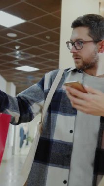 Yoğun bir alışveriş alanında, bir erkek ve bir kadın cep telefonuyla bir anın tadını çıkarırlar. Kadın vitrinlere bakarken, adam telefonda çantalarla hokkabazlık yapıyor.