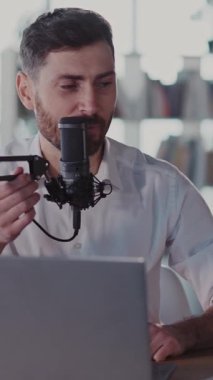 Beyaz gömlekli neşeli sakallı bir adam dizüstü bilgisayarı mikrofonuyla canlı bir tartışmaya girişiyor. Pozitif ve coşkulu bir görüntü sergiliyor.