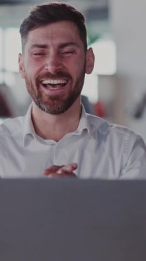 Sakallı bir adam masada dizüstü bilgisayar kullanmaktan hoşlanır. Gülümser ve yakınındaki yiyeceklerle rahatlar. Bu video neşe, üretkenlik ve iş hayatı dengesini iletir