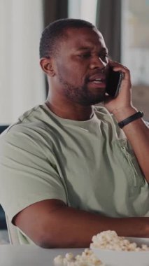 Bir adam canlı bir telefonda masada patlamış mısırın tadını çıkarıyor. Bu sahne rahatlatıcı bir atmosferi anlamlı bir bağlılıkla harmanlıyor.