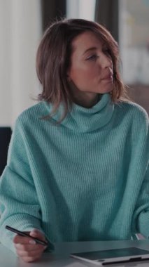 Video, masadaki mavi kazaklı bir kadının tabletine ve telefonuna odaklandığını gösteriyor. Modern ve bağlantılı bir yaşam tarzını ön plana çıkarıyor.