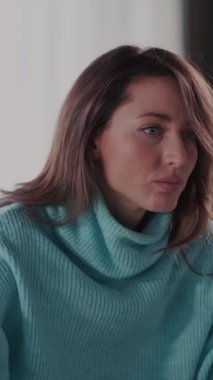 Videoda mavi kazaklı bir kadın var. Kameraya yakından bakıyor, sonra komik yüzünü gösteriyor ve kanepede dinleniyor.