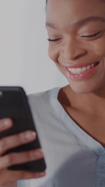 Neşeli bir kadın cep telefonuna gülümsüyor, ekranda gördüklerinden mutluluk yayıyor, neşeli bir anı yakalıyor.