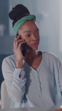 Yeşil bantlı genç bir kadın cep telefonunda sohbet ediyor, merak ve iletişimi ifadeleri değişirken gösteriyor, heyecanı yansıtıyor.