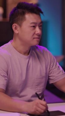 İki adam bir masada canlı bir tartışmaya girişiyor. Biri, mor gömlekli, bir not panosuyla not alırken, pembe koruyucu ailelerle işbirliği içinde gülümseyen meslektaşı...