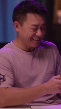 Mor gömlekli bir adam, mikrofona olumlu düşünceler yerleştirir. Telefonunu kontrol ederken gülümser, davetkar ve canlandırıcı bir atmosfer yaratır.