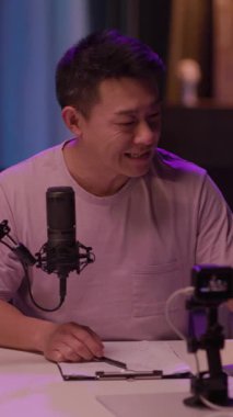 Bu ilgi çekici videoda, bir adam bir masaya oturur, dizüstü bilgisayarı ve mikrofonuna odaklanır. Atmosfer üretken, modern bir çalışma alanı sergiliyor.