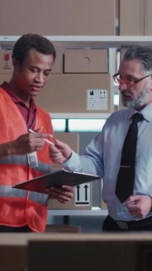 Postane. Çoklu Irkçı Erkek İşçiler Depo Odası Bölümü 'nde Teslimat Bilgileri ve Paketleri Birleştirmeyi Tartışıyor. İşbirliği. Tokalaşma.