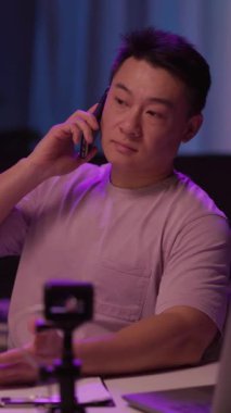 Bir adam rahat bir şekilde bir masada oturuyor, cep telefonuyla konuşuyor, muhtemelen önemli bir şeyi tartışıyor.