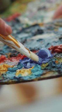 Sanatçının elleri bir fırça ve palet tutuyor. Boyayla çiz. Stüdyoda. Tuval. Ağır çekim. RED Epic Camera 'da Çekim.