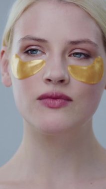 Bir kadın, son moda cilt bakımını vurgulayarak lüks altın göz maskeleri takarak kendini koruma rutininden zevk alır.