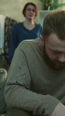 Sinirli genç bir kadın bir adama vuruyor bir alkolik kanepeye oturuyor bira içiyor üzgün stres, alkolik ev umutsuz mutsuz alkolik adam yorgun şişe ağır çekimde portre yakın çekim