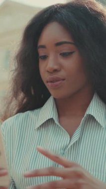 Akıllı telefonuna odaklanmış genç bir kadın açık hava ortamında modern bir bağlantı sergiliyor..