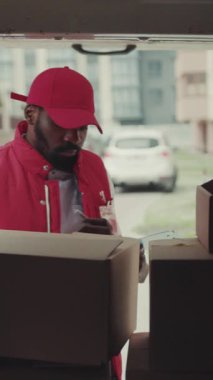 Bir kuryenin yakınına genç bir Afro-Amerikan adam arabadan bir kutu alır ve teslimat için posta üniforması taşır güçlü nakliye koliyatı hizmeti ağır çekim yetişkin koordinasyonu