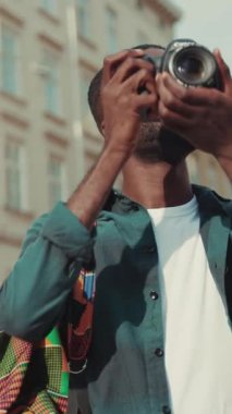 Moda gözlüklü şık bir genç adam güvenli bir şekilde dışarıda duruyor, çağdaş kentsel titreşimler yayıyor.