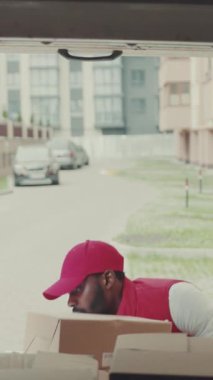 Yüz kuryesi Afro-Amerikan genç adam kutuları arabaya koydu teslimat işi posta üniforması taşıdı güçlü nakliye paketi taşıdı yetişkin yakın çekim portre koordinasyonu yavaş çekim