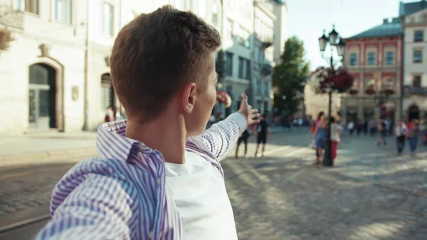 Genç adam, kamerayı tut ve şehrin etrafında gülümse. Sokakta konuş çocuk. Yavaş çekim yaşam tarzı, Kafkasyalı, neşeli çocuk, yavaş çekim moda öğrencisi.