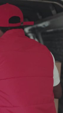 Yüzünüzü kapatın yakışıklı kurye Afro-Amerikan genç adam kameraya bakın gülümseme portresi posta üniforması işçi karton sonra ticari dağıtım kutusu lojistik servis