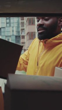 Gülümseyen kurye Afro-Amerikan açık araba teslimat cihazı, karton teknoloji kutusu siparişi, posta kutusu postası, sakallı, lojistik postacı...