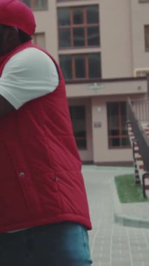 Mutlu kurye Afro-Amerikan genç adam kutusunu arabadan çıkardı ve gülümseme portresi, karton teknoloji kutusu siparişi posta kutusu, sakal, lojistik postacı.