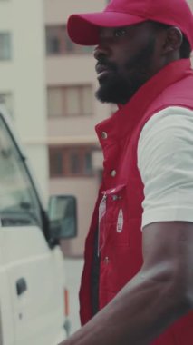 NEW YORK - 5 Nisan 2017: Kurye Afro-Amerikan genç adam kutusunu arabadan çıkardı ve telefon gülümseme portresi karton kutu siparişi postacı sakalı