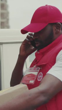 NEW YORK - 5 Nisan 2017: Gülümseyen kurye Afro-Amerikan genç adam kutuyu arabadan çıkardı telefon portresi teknolojisi sipariş kutusundan posta kutusuna sipariş etti.