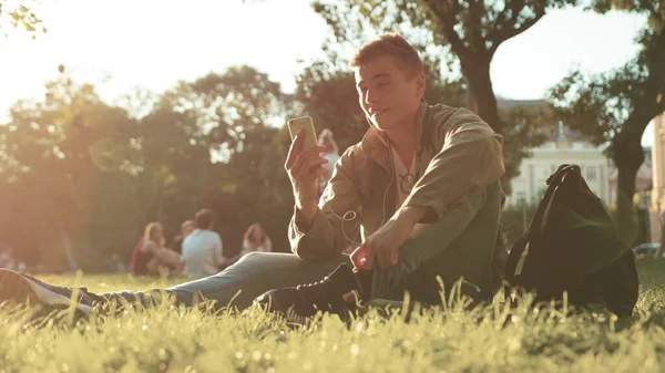 Parkta oturmuş akıllı telefon kullanan sıradan bir adam mutlu bir şekilde konuşur günbatımında konuşan bir öğrenci elinde yakışıklı bir mesaj taşıyan bir çocuk elinde Kafkas ağır çekimde yakın çekimde bir portre