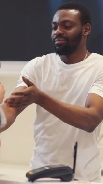 Beyaz t-shirt giyen genç bir adam neşeli bir gülümseme ile kendine güvenir ve neşeli bir çevrede durur.